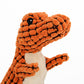 Dog holding orange dinosaur plush toy