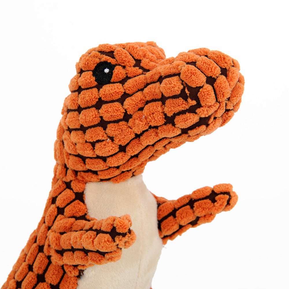 Dog holding orange dinosaur plush toy
